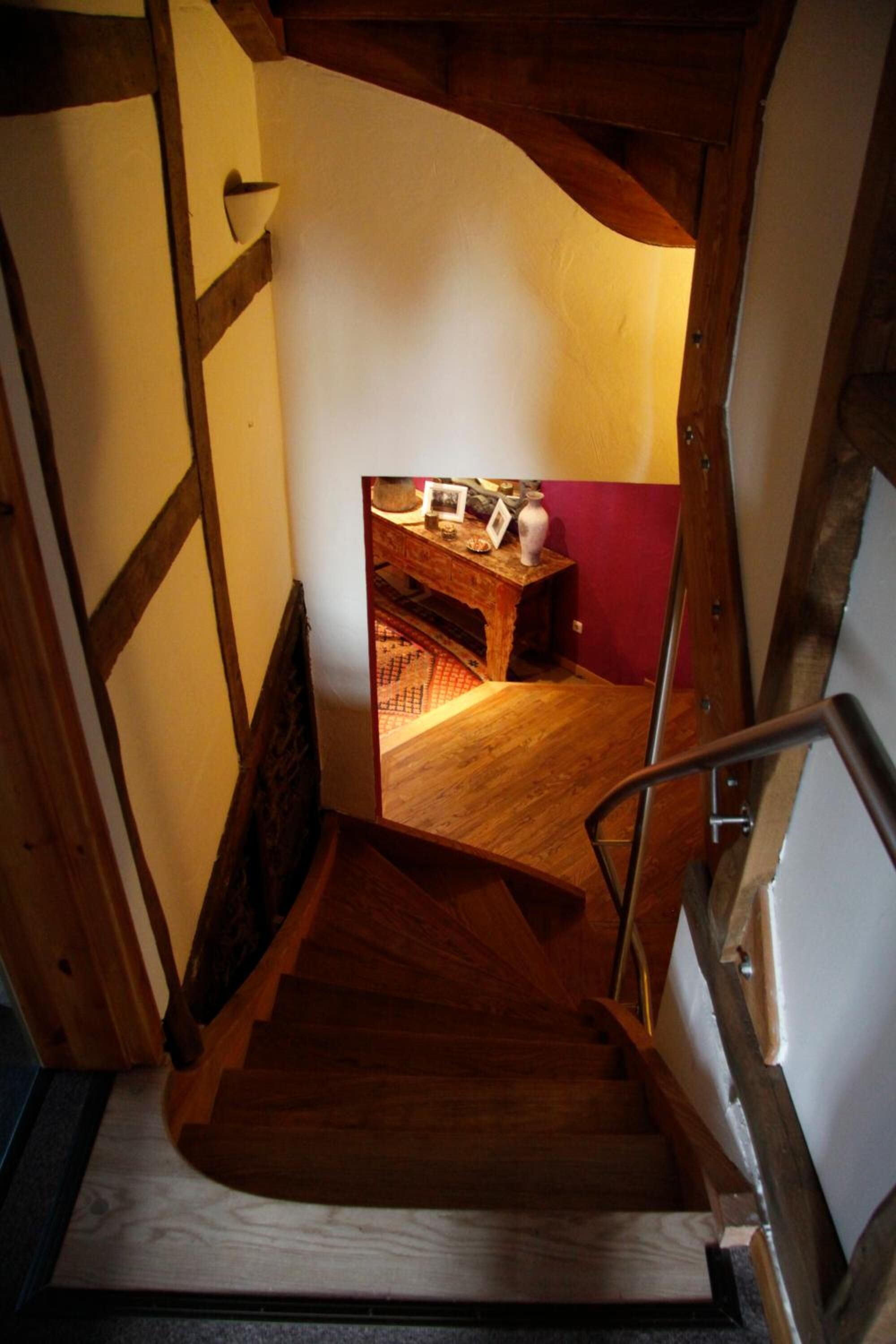 Eine Holztreppe führt zu einem Raum mit einem kleinen Tisch und einer Vase.
