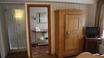 A bathroom with a shower, sink, and cabinet.