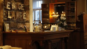 Un espace bar avec un mur en pierre, un comptoir en bois et un miroir qui reflète l’intérieur.