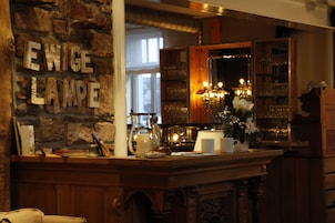 Zona de bar con pared de piedra, mostrador de madera y espejo que refleja el interior.