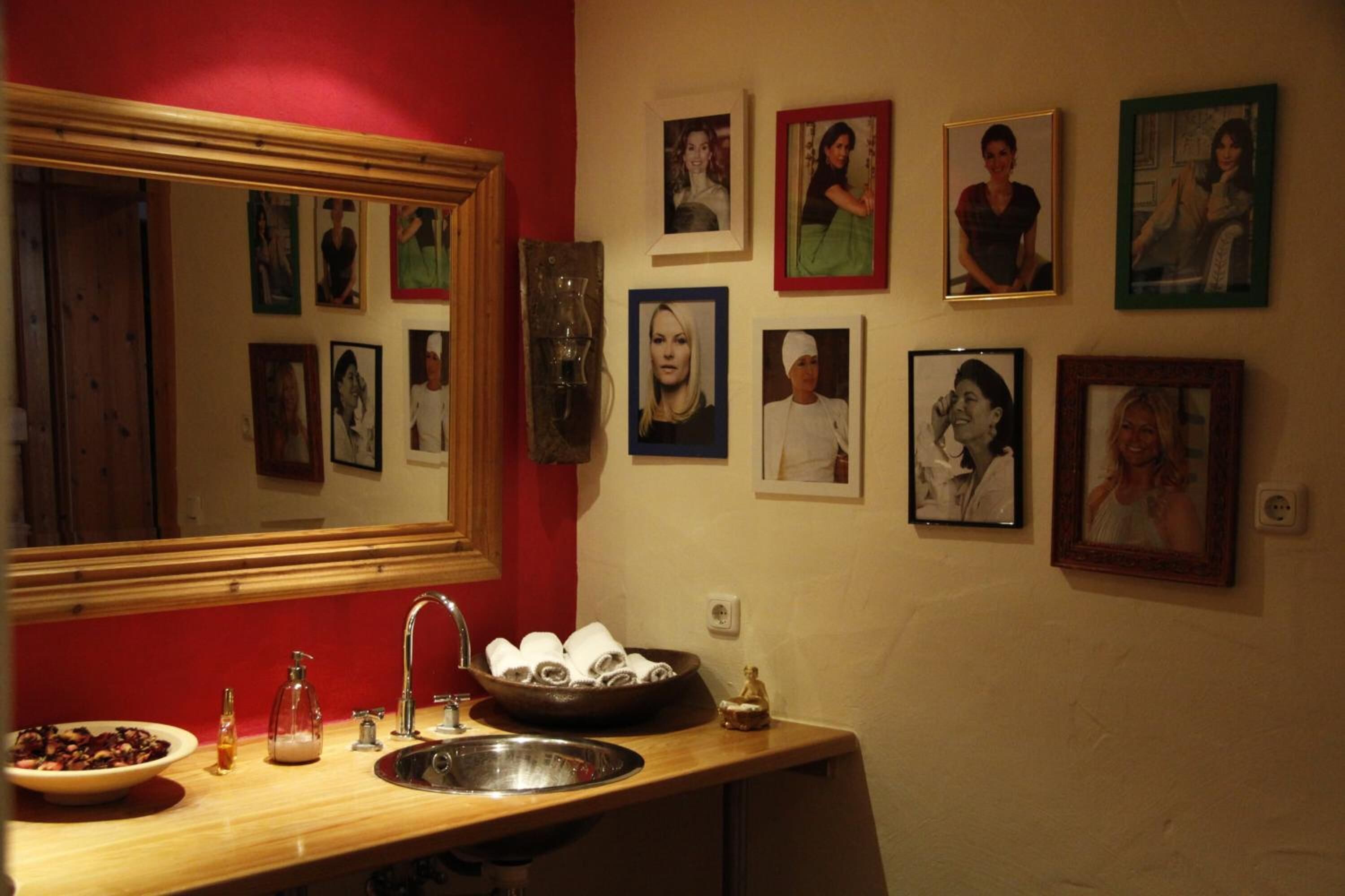 Une cuisine avec un plan de travail en bois, un évier et un miroir. Des tableaux encadrés ornent le mur et un panier rempli de serviettes est posé sur le plan de travail.