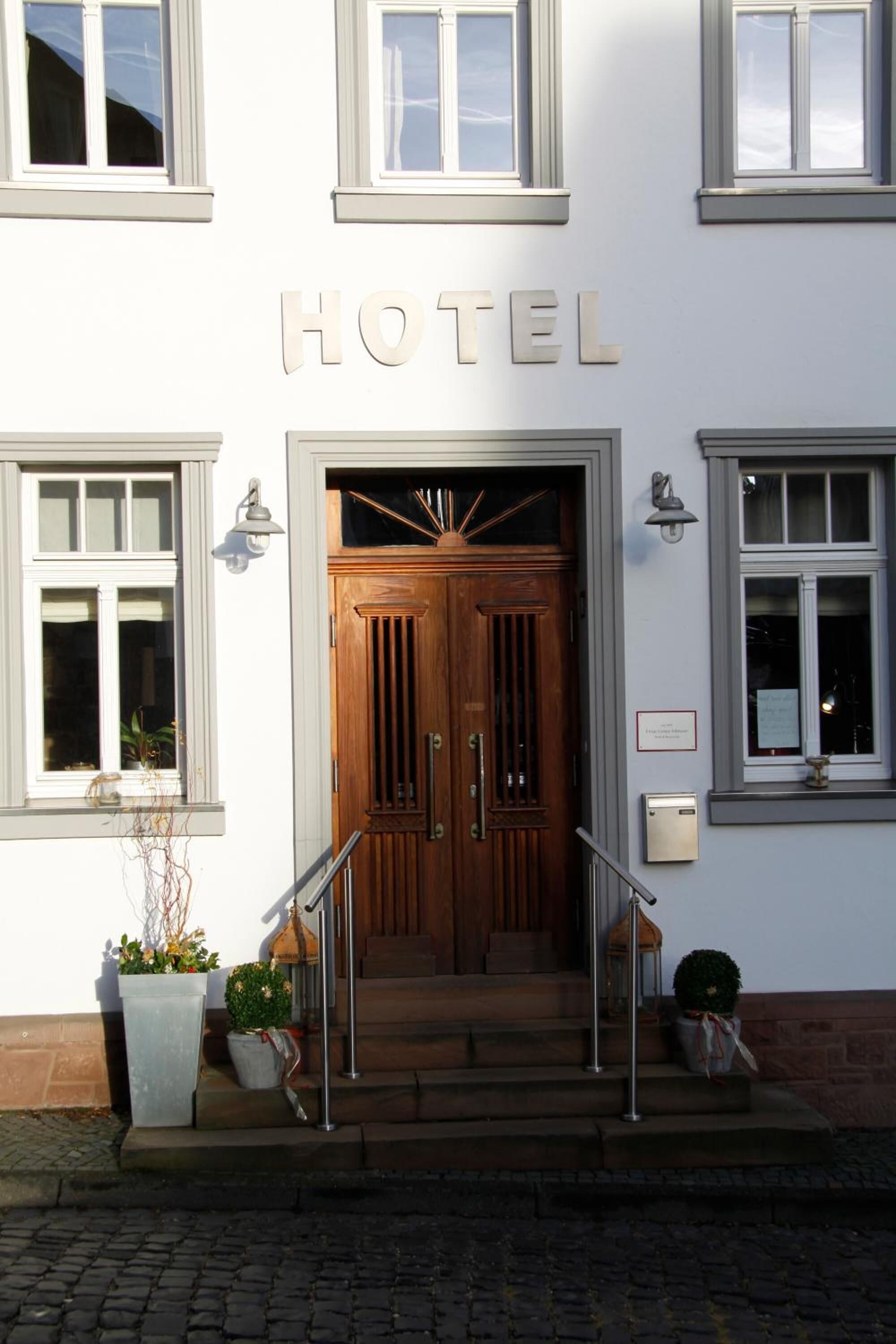 A hotel entrance with a wooden double door, a staircase leading up, and a sign above the door that reads "HOTEL".