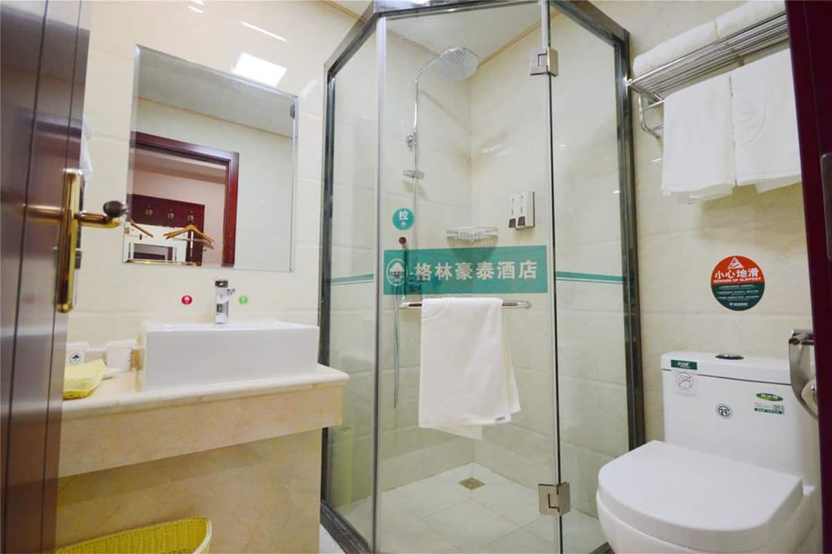 A hotel bathroom with a glass-enclosed shower, a sink, and a toilet.