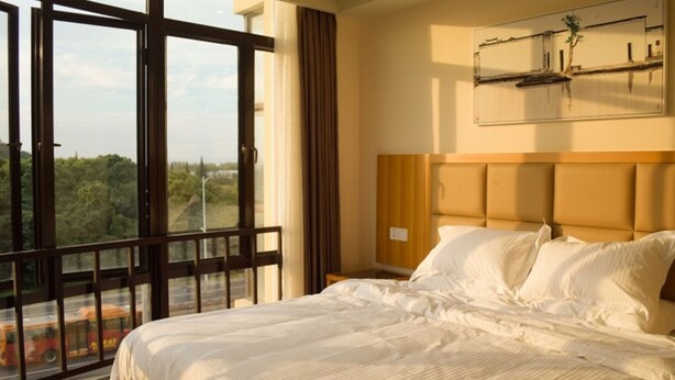 A hotel room with a large bed, a view of greenery outside, and a painting on the wall. - GreenTree AnHui Wuhu Sanshan Development District Express Hotel (Wuhu)