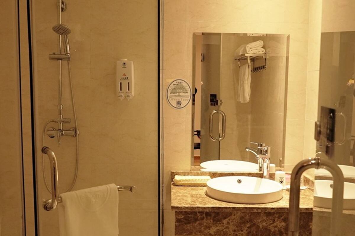 A bathroom with a glass shower enclosure, a towel rack, a sink, and a mirror.