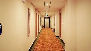 A hotel corridor with a carpeted floor, doors on both sides, and a fire extinguisher on the right wall. - GreenTree Inn Beihai HePu County South Huanzhu Road Express Hotel (Beihai)
