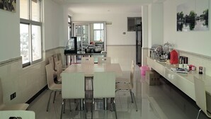 A modern kitchen with a dining area, large windows, and a view of the city. - GreenTree Inn Beihai HePu County South Huanzhu Road Express Hotel (Beihai)