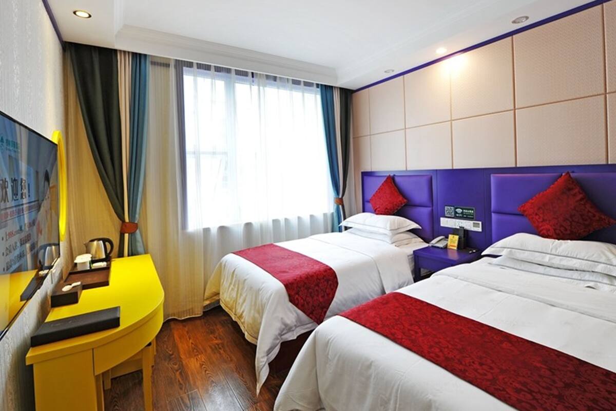 A hotel room with two beds, a desk, and a television.