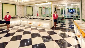 Zona de bufé con piso a cuadros, mostradores de comida y personal con uniforme.