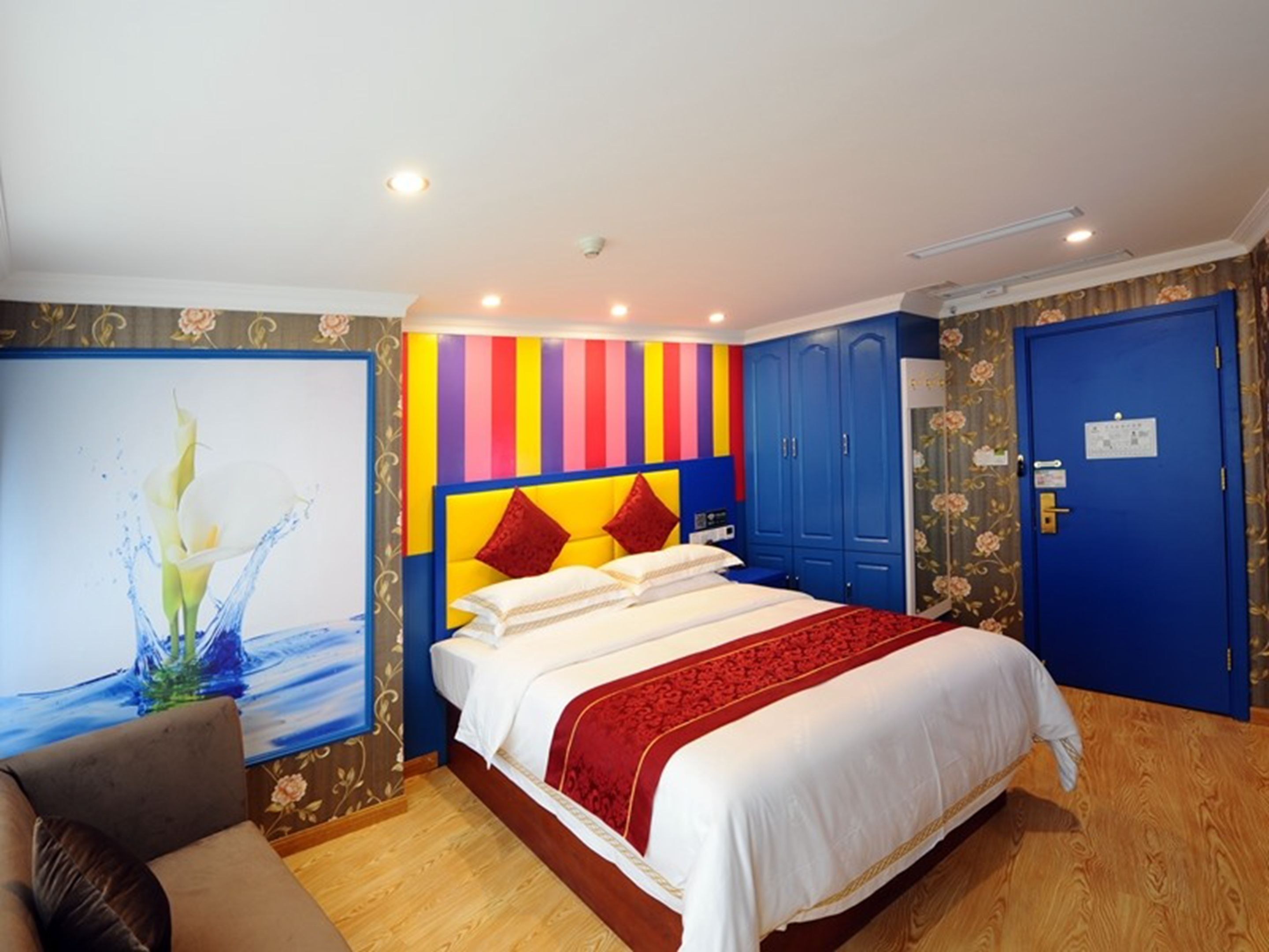 Une chambre d’hôtel avec un lit, une armoire bleue, une porte avec une serrure et un tableau accroché au mur.