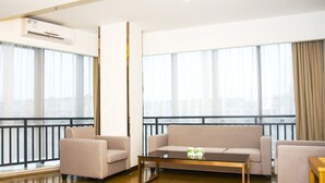 Un salon moderne avec un ensemble de canapés, une table basse et de grandes fenêtres dotées de rideaux.
