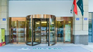Une entrée moderne avec une porte tournante, des portes vitrées et des drapeaux.