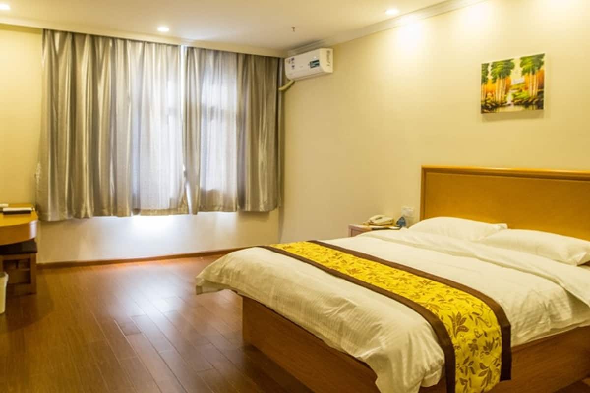 Una habitación de hotel con una cama de madera, una mesita de noche, un teléfono y una ventana con cortinas.