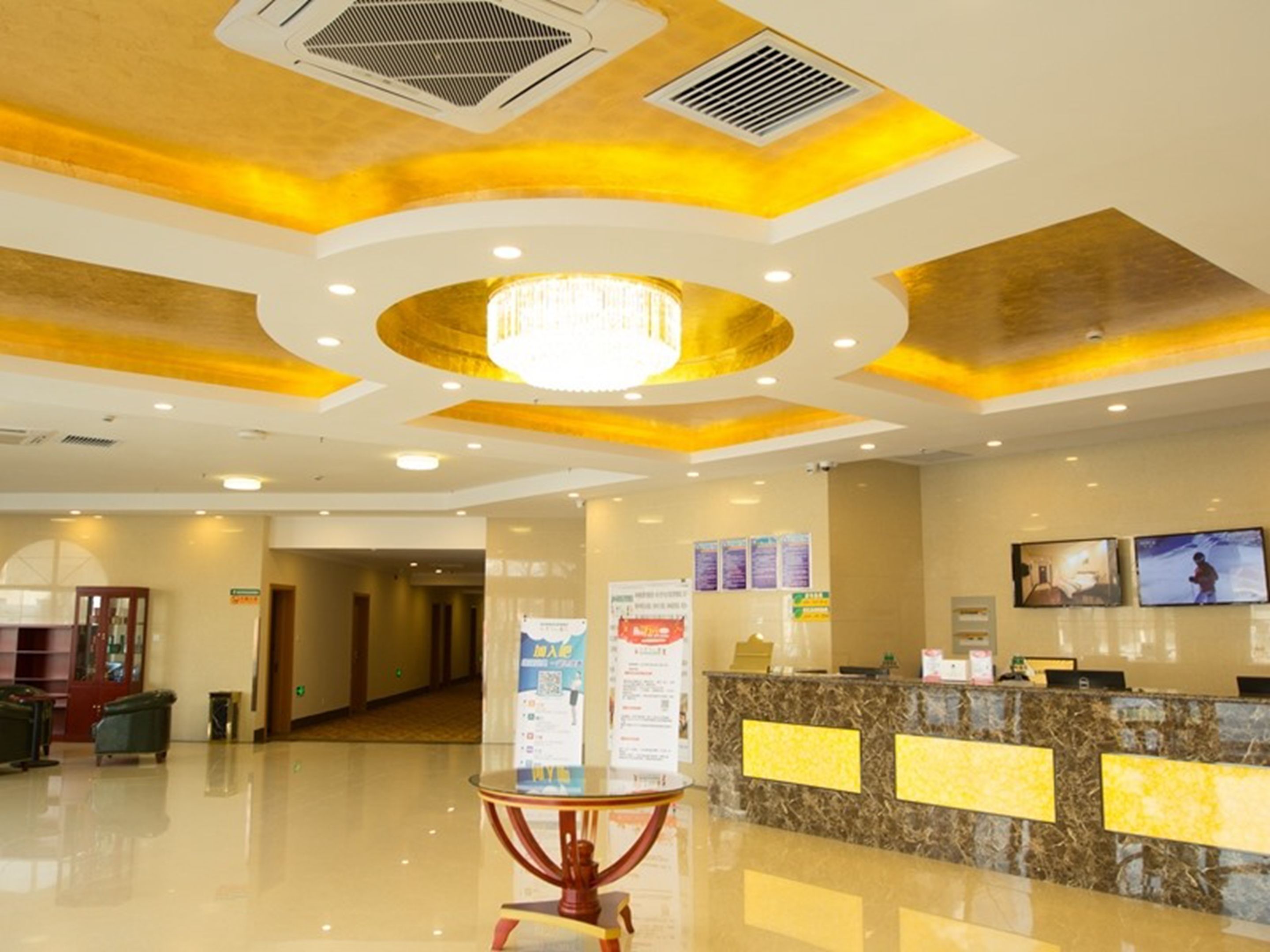A hotel lobby with a reception desk, a chandelier, and a clean, polished floor.