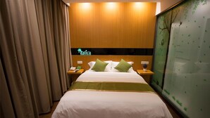 A hotel room with a bed, nightstands, a green wall with a tree decal, and a sign that reads "Yatica." - Vatica XuZhou WanDa Plaza Hotel (Xuzhou)