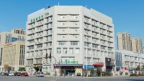 A multi-story hotel with a central courtyard, surrounded by other buildings. - Vatica XuZhou WanDa Plaza Hotel (Xuzhou)