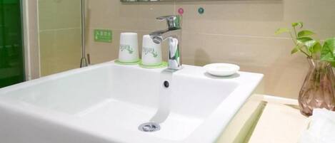 Un baño con un lavamanos blanco, un espejo y una planta verde.
