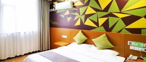 Habitación de hotel con cama, mesita de noche, aire acondicionado instalado en la pared y un muro con estampado geométrico.