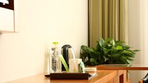 A wooden desk with a plant, a bottle, and a mug. - Vatica XuZhou WanDa Plaza Hotel (Xuzhou)