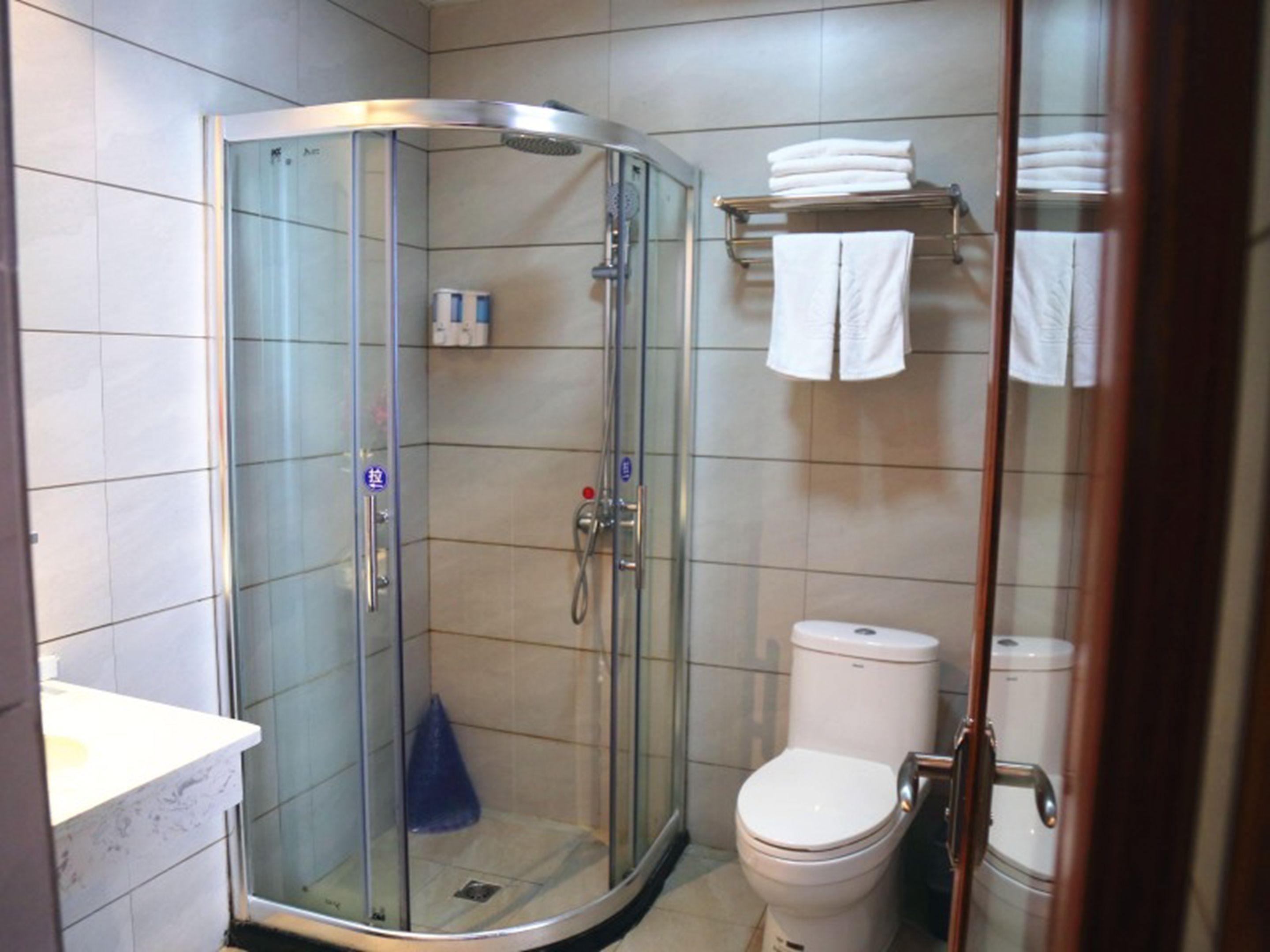 A modern bathroom with a glass-enclosed shower, a toilet, and a sink.