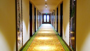 A long, narrow hallway with a patterned carpet, flanked by walls with framed artwork. - GreenTree Aliiance Weifang Zhucheng Heping Street Huayang Hotel (Weifang)