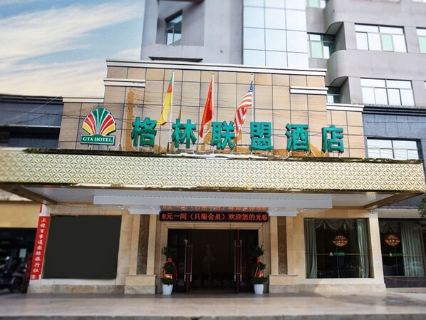 A hotel with a modern facade, a visible entrance, and a sign indicating a price of 8 yuan per person.