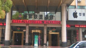 L’entrée d’un hôtel, avec une grande enseigne en caractères chinois, un écran numérique au-dessus de l’entrée et un magasin Apple sur la droite.