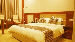 Une chambre d’hôtel avec un grand lit, une table de chevet avec une lampe, une chaise et un bureau avec un téléphone.
