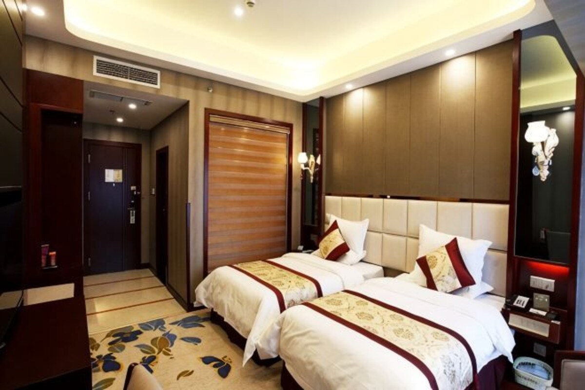 Une chambre d’hôtel avec deux lits, une télévision, une armoire et une salle de bain.
