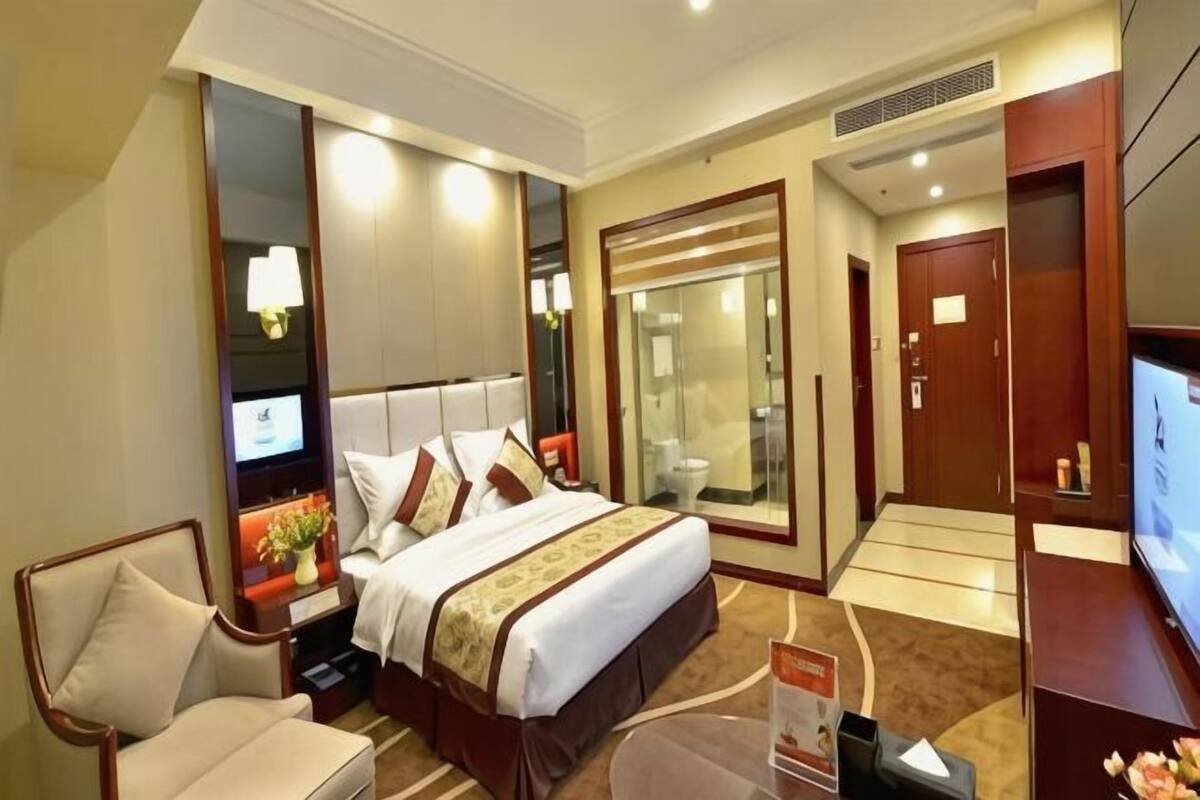 Una habitación de hotel con una cama grande, televisión, escritorio y baño.