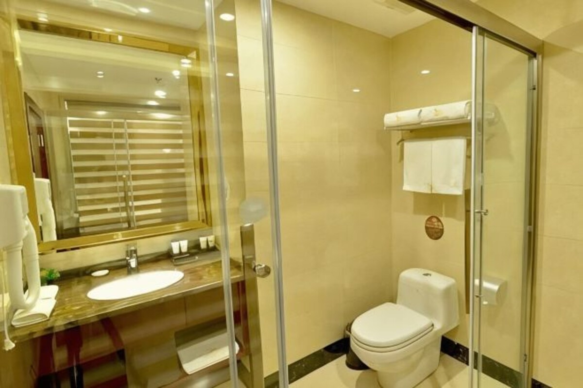 Une salle de bain avec une douche à parois de verre, un lavabo, des toilettes et un miroir avec un cadre doré.