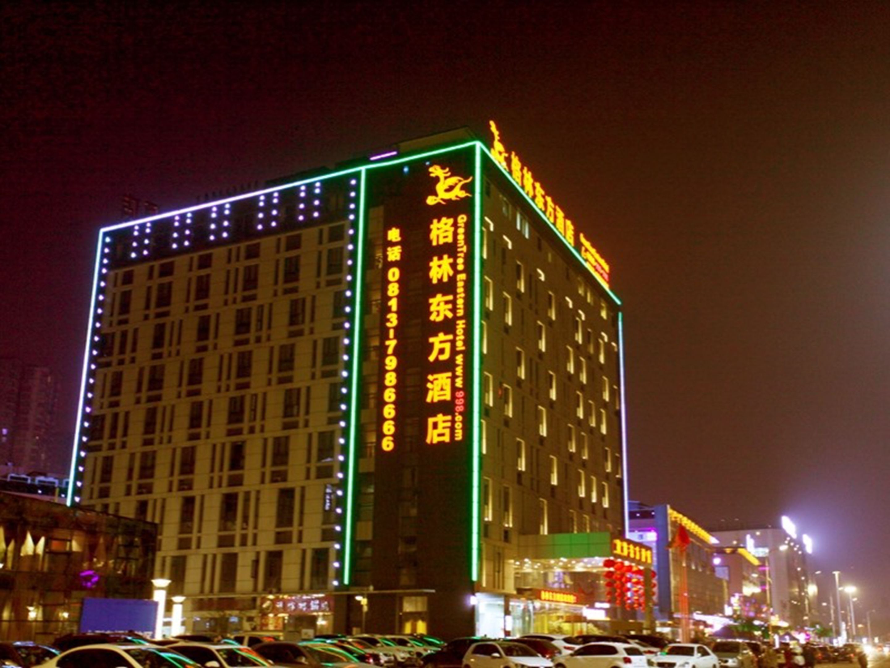 A hotel with illuminated signage and a vertical strip of text on the facade.