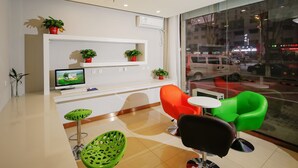 A modern reception area with a TV, seating, and potted plants. - Shell Langfang GuAn County Bus Station Hotel (Langfang)