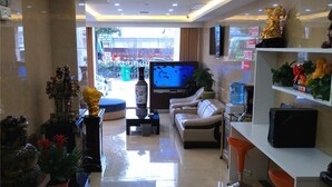 Een moderne hotellobby met een bank, een televisie, decoratieve objecten en een waterdispenser.