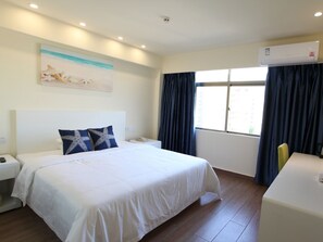 Une chambre d’hôtel avec un grand lit, un bureau, un téléphone et une fenêtre avec des rideaux.