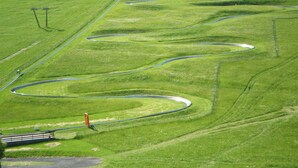 A green landscape with winding paths and a small structure. - Hotel Residence La Rosa (Castione della Presolana)