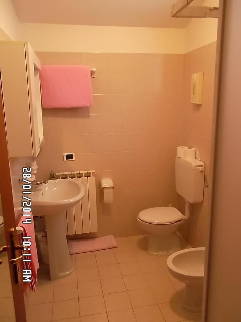 Une salle de bain équipée d’un lavabo, de toilettes et d’un porte-serviettes.