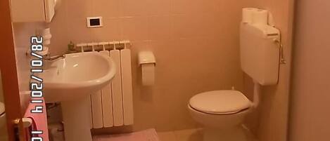 Une salle de bain équipée d’un lavabo, de toilettes et d’un porte-serviettes.