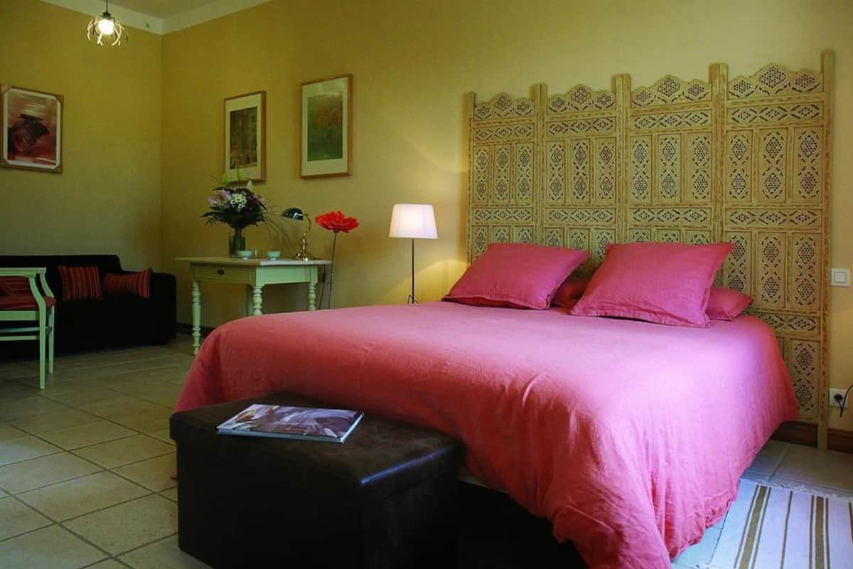 A hotel room with a bed, a desk, a chair, and a lamp.