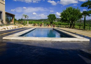 A rectangular pool with a stone border, surrounded by a landscaped garden with various plants and trees. - Château La Sabine (Saint-Laurent-de-la-Cabrerisse)
