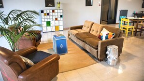 A living room with a brown sofa, a blue storage unit, and a large plant. - Lako Hostel (Capodimonte)