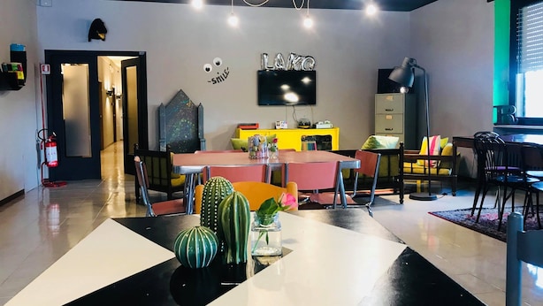 A modern dining area with a central table, chairs, and decorative plants. - Lako Hostel (Capodimonte)