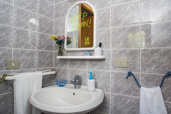 Un baño con lavamanos blanco, un espejo y un perchero para toallas.