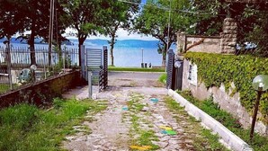 A pathway leading to a body of water, flanked by a stone wall and metal gates. - Lako Hostel (Capodimonte)
