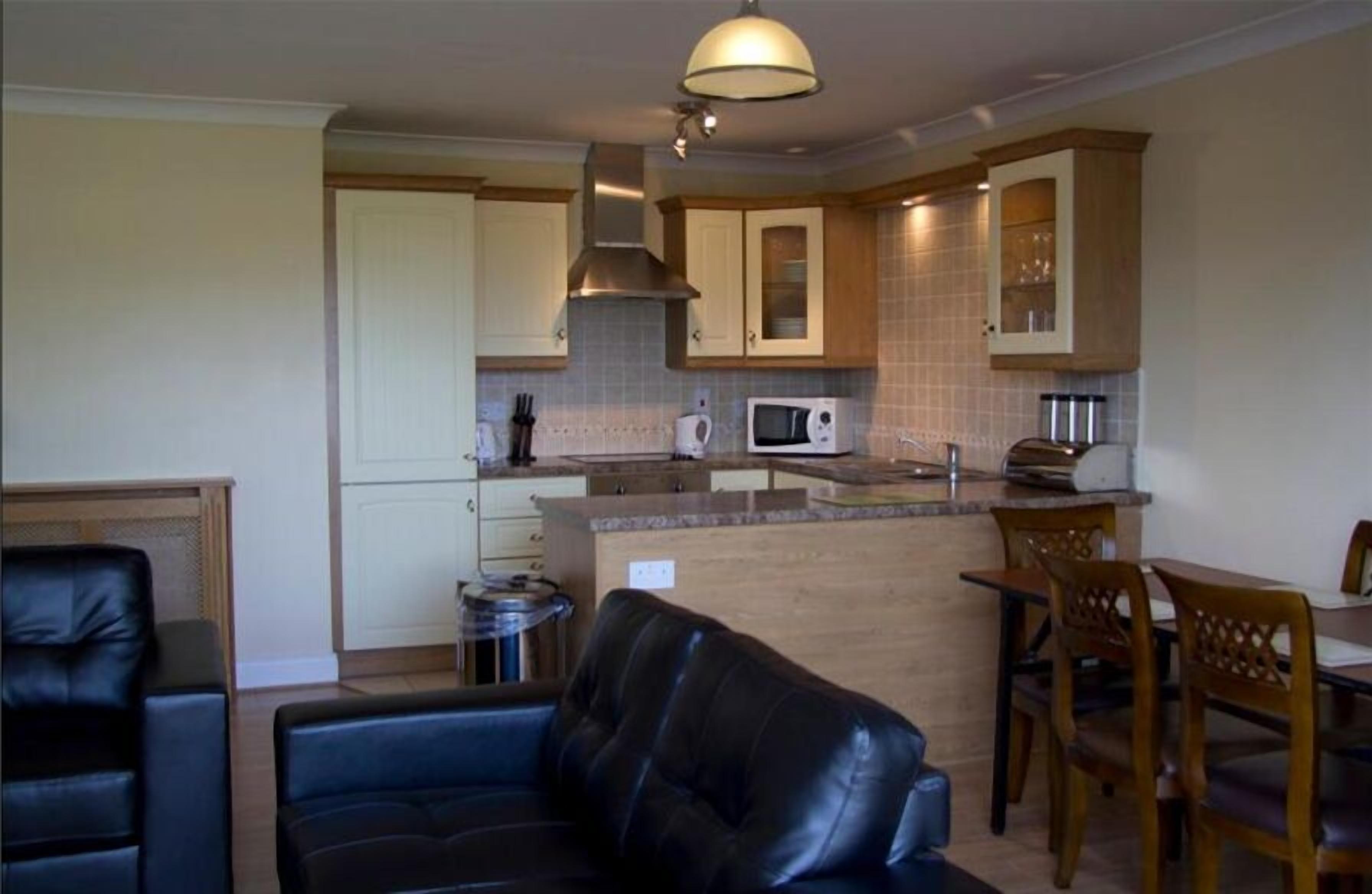 A compact kitchen with a microwave, stove, and cabinets. There is a dining area with a table and chairs.