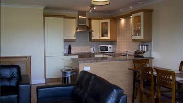 A compact kitchen with a microwave, stove, and cabinets. There is a dining area with a table and chairs.