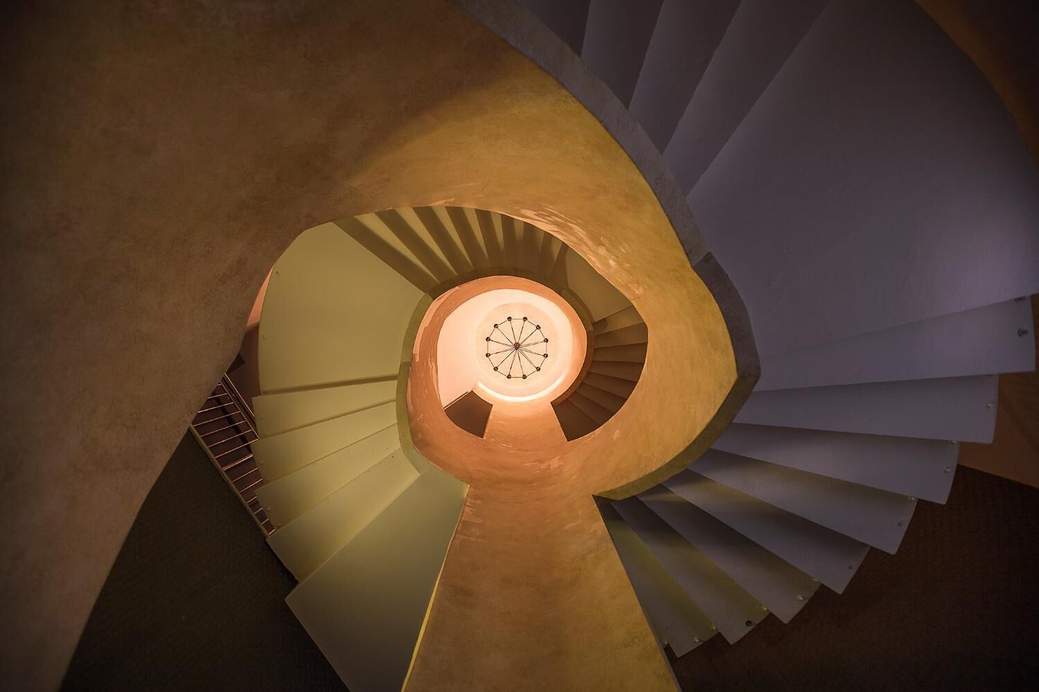 Una escalera de caracol con un elemento circular iluminado en el centro.