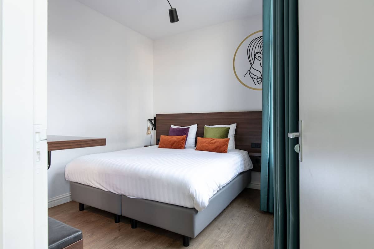 A bedroom with a bed, bedside table, and a wall-mounted light fixture.