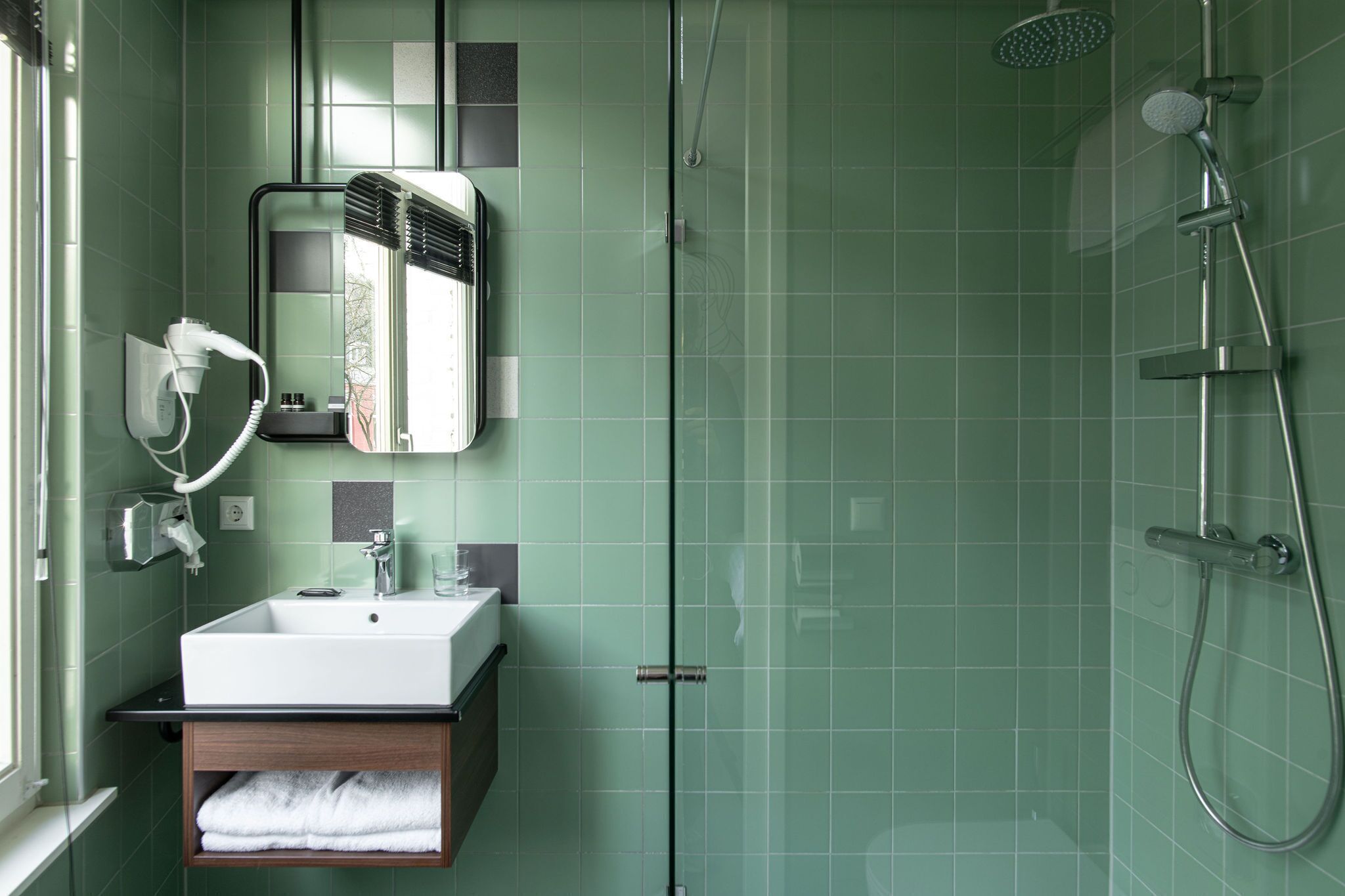 A bathroom with a sink, mirror, and shower.