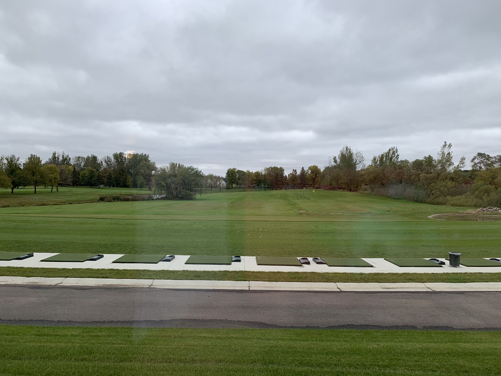 Een golfbaan met een verzorgd gazon, een oefenveld en een heldere lucht.